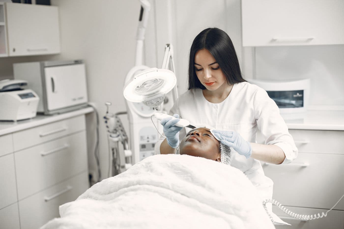 Clinician performing an aesthetic treatment on a patient in a bright modern clinic room